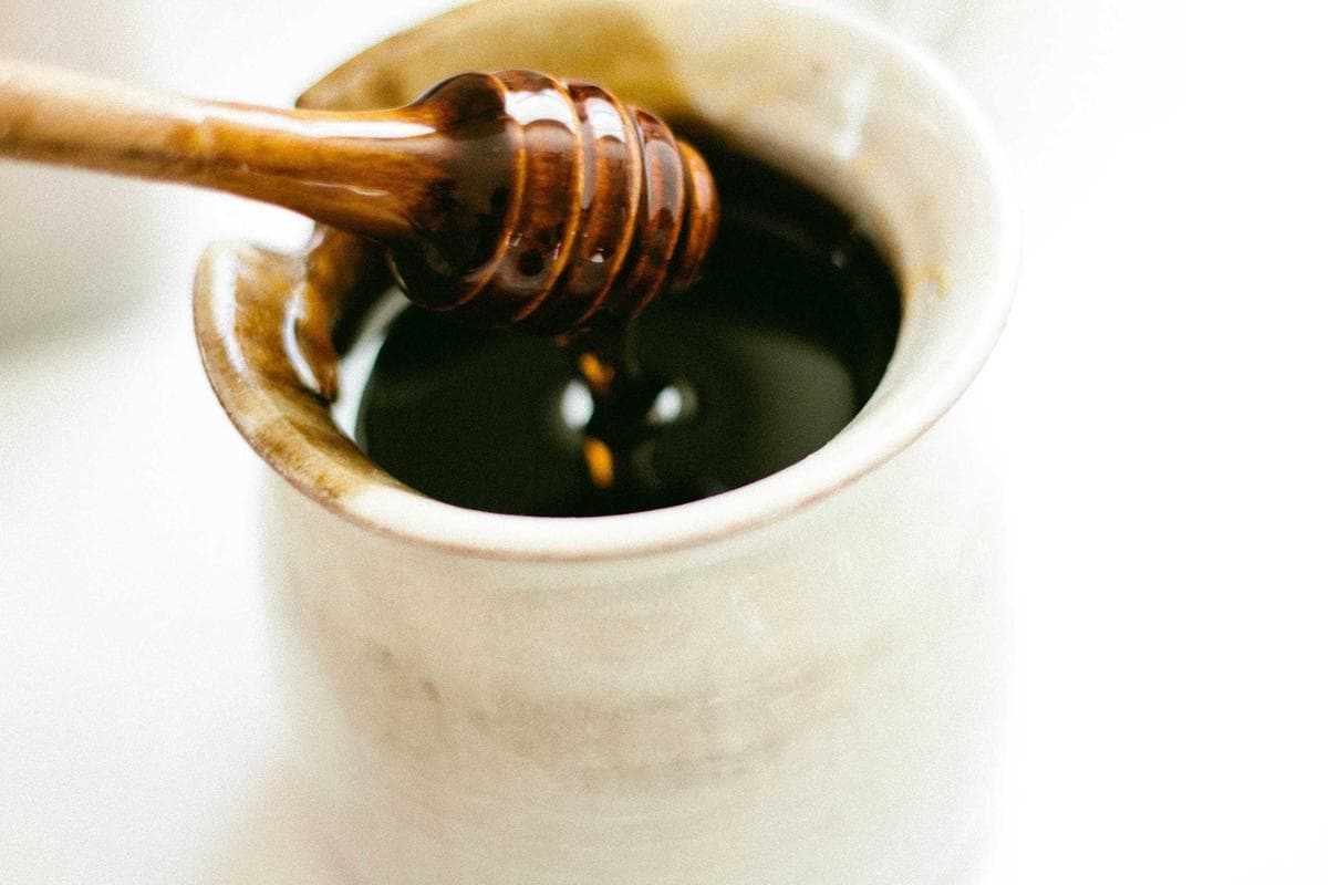 Honey dipper resting in a ceramic pot, warm close-up
